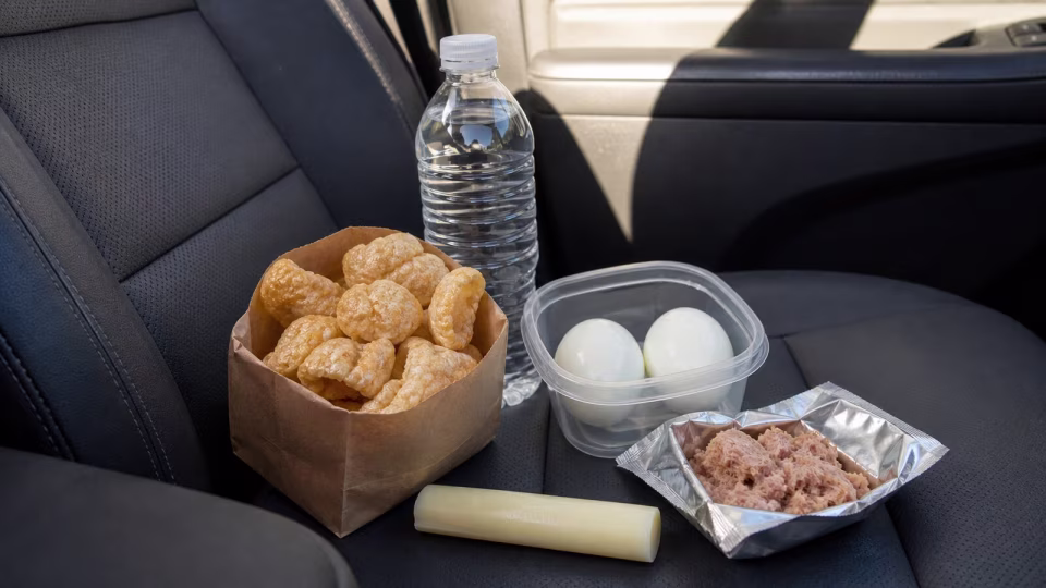 Unbranded keto emergency foods arranged on a car seat for a road trip.